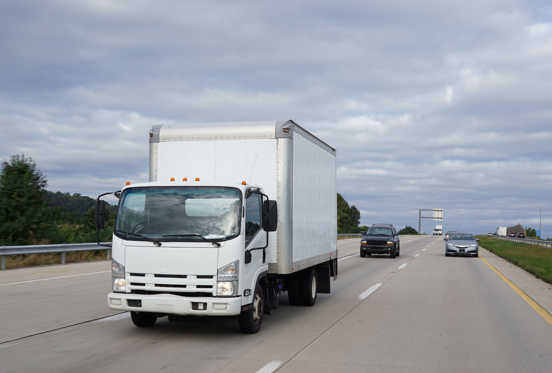 White cab-over light duty truck on highway delivering goods